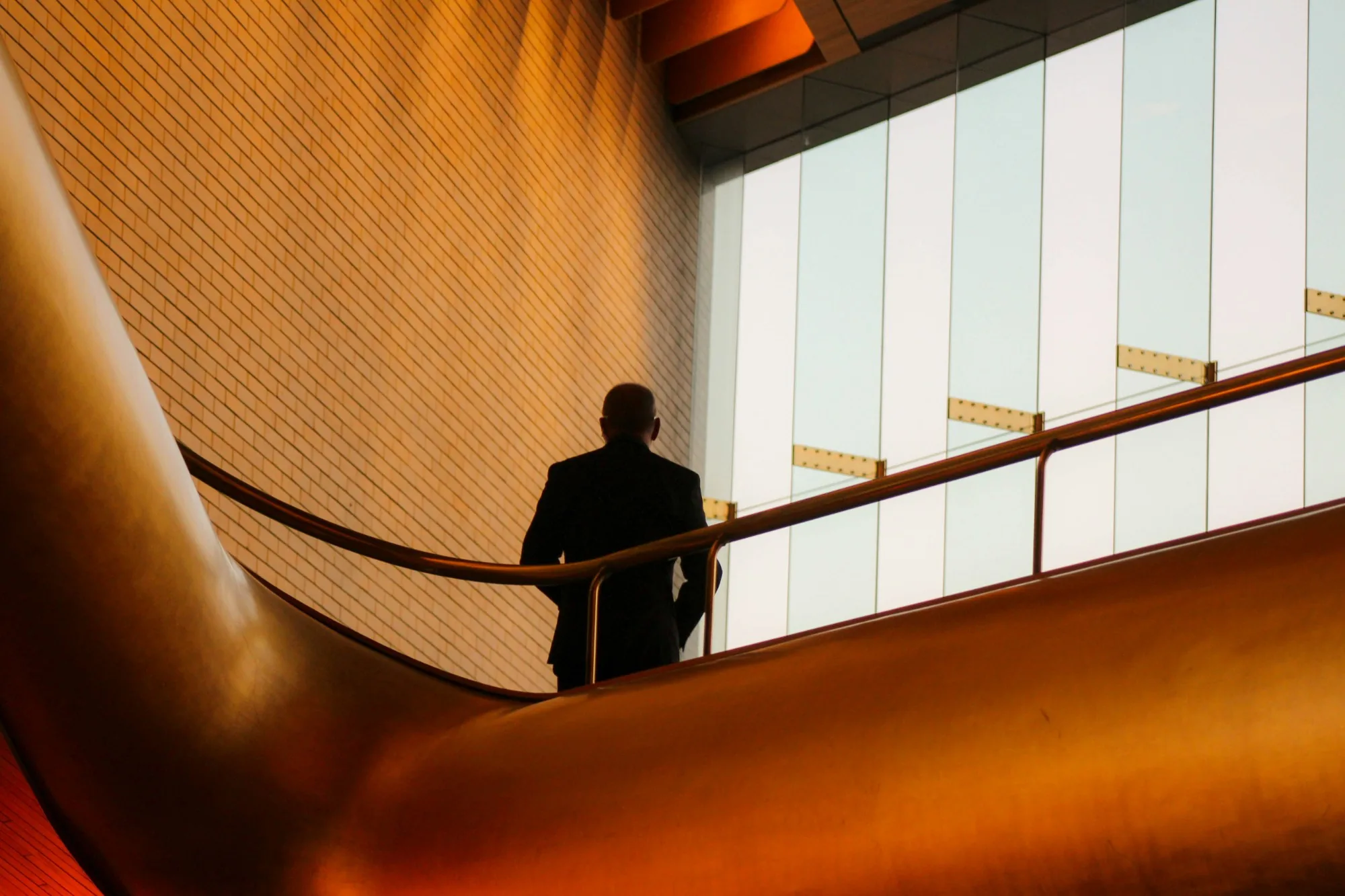 A man in a suit looking out from a gold curved staircase