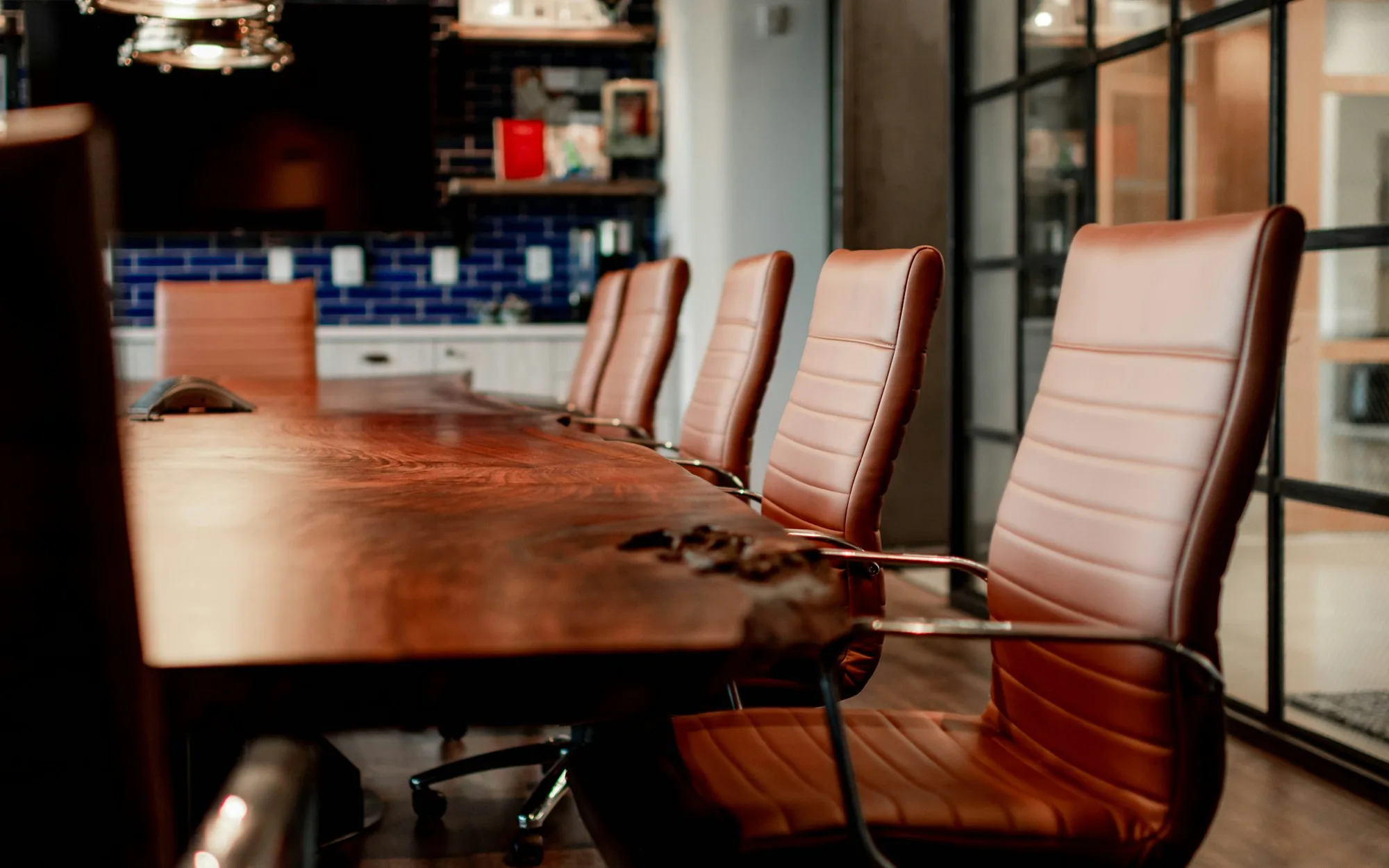 An empty boardroom with leather chairs around a long wooden table