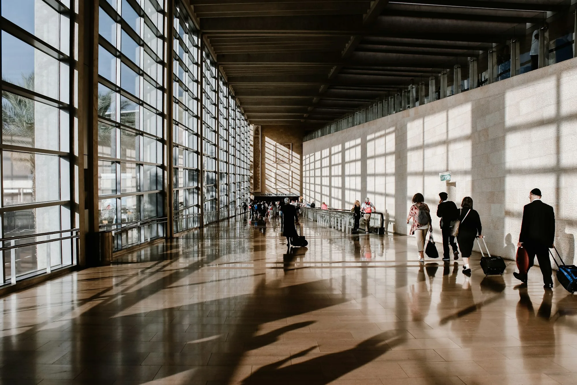 People walking through a sunlit airport terminal